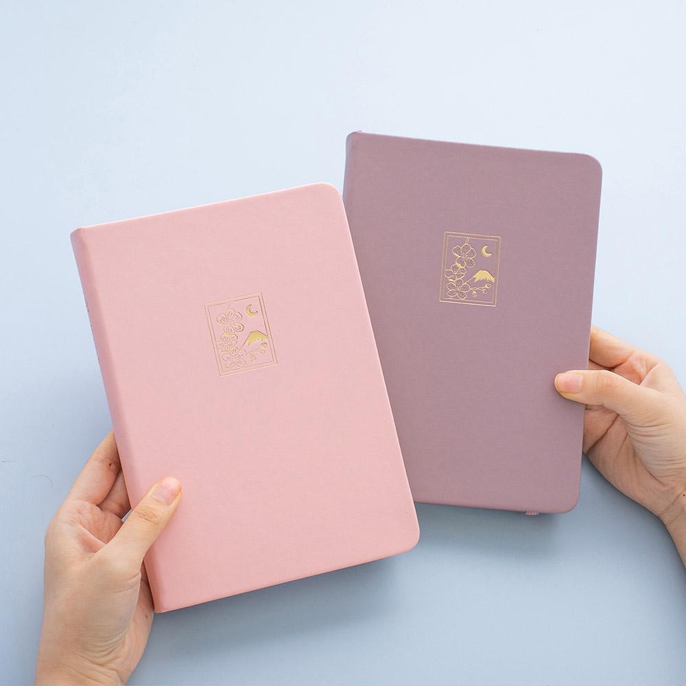 Tsuki 'Sakura' Limited Edition Bullet Journal in blush pink and petal pink held in hands in light blue background
