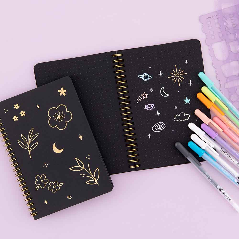 Open and closed Tsuki Black Paper Ringbound Bullet Journals with Gelly Roll Pens and Tsuki Bullet Journal Stencil Set in Lilac Taro on lilac background