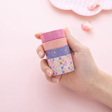 Stacked Tsuki Floral washi tapes held in hand on pink background