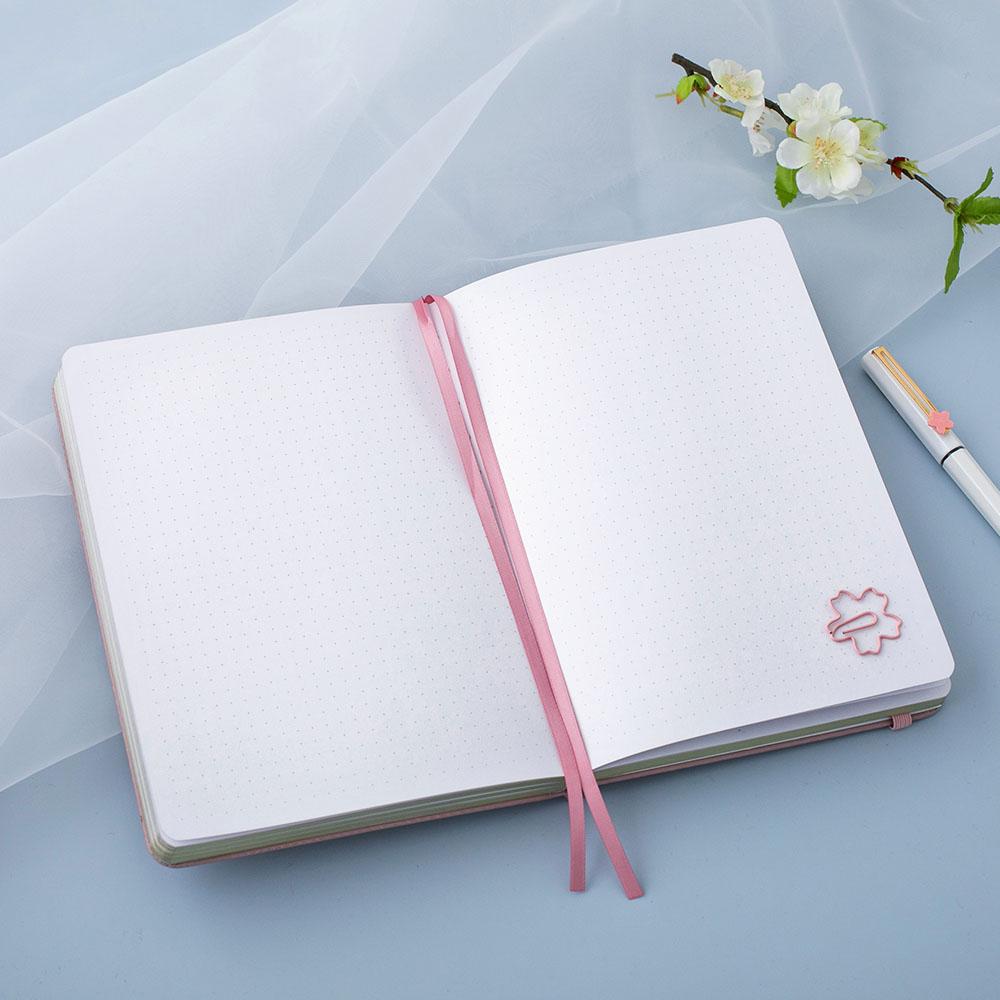 Open Tsuki 'Sakura' Limited Edition Bullet Journal with paperclip gift with white pen and flower branch on white netting on light blue background