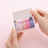 Tsuki Floral washi tapes in boxed packaging held in hands, on pink background