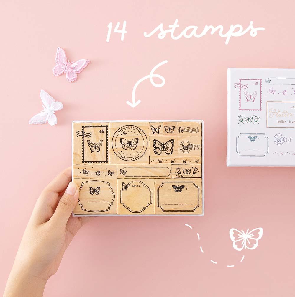 Tsuki ‘Flutter + Dream’ Bullet Journal Stamp Set by Notebook Therapy x Pelinkan with fourteen stamps held in hands with butterflies in pastel pink background