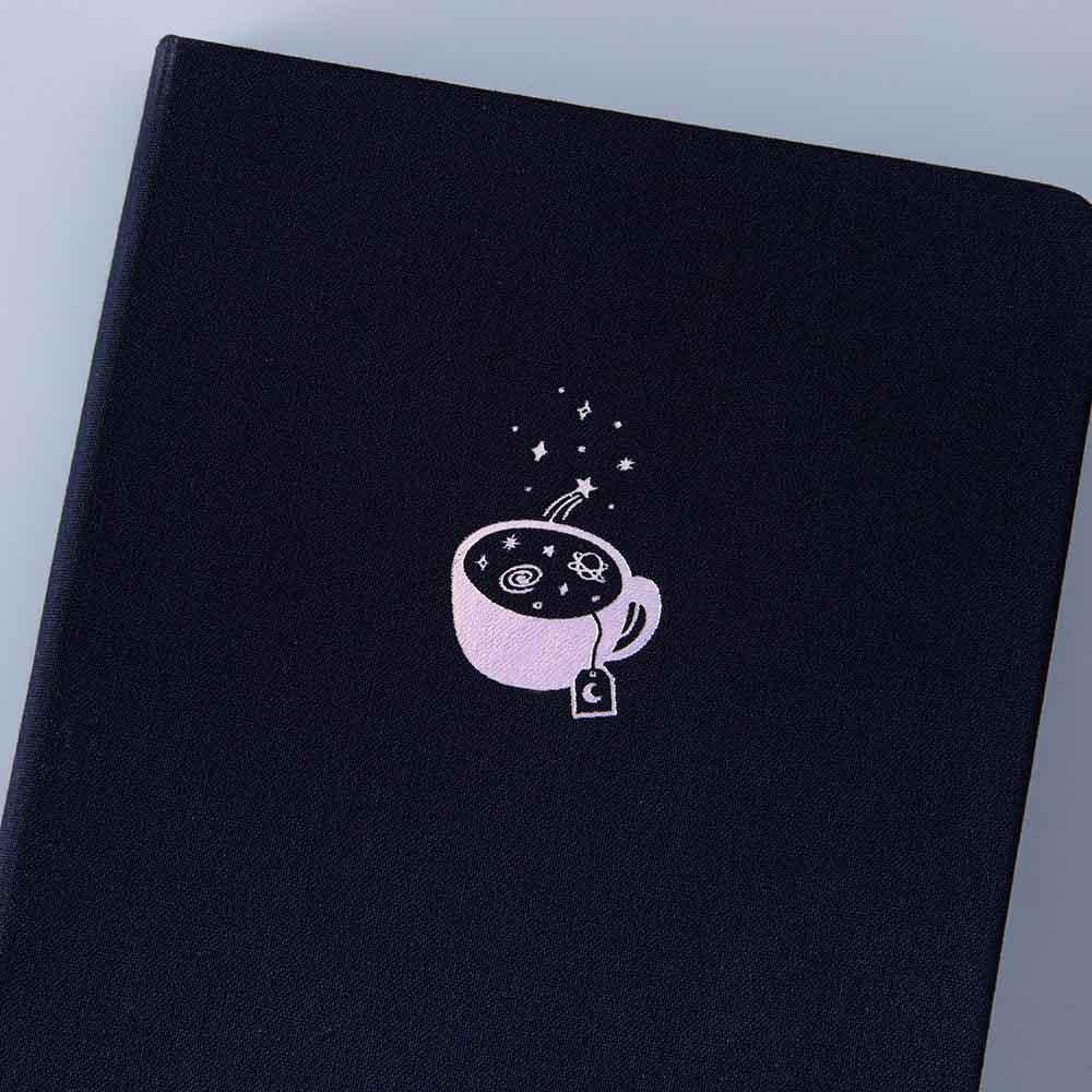 Close up of the front cover of Tsuki ‘Cup of Galaxy’ Limited Edition Holographic Bullet Journal on light blue background