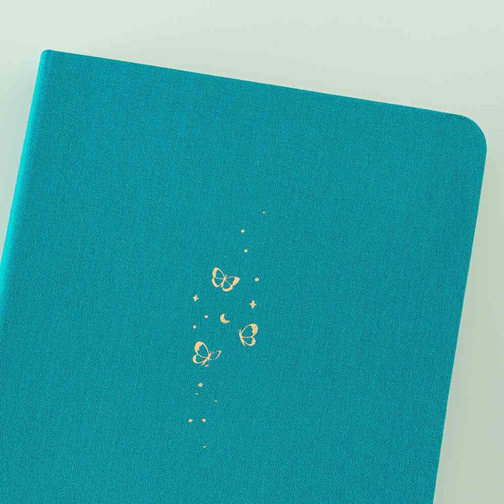 Close up of the front cover of Tsuki Teal Sky ‘Flutter + Dream’ Limited Edition Bullet Journal by Notebook Therapy x Pelinkan on mint background