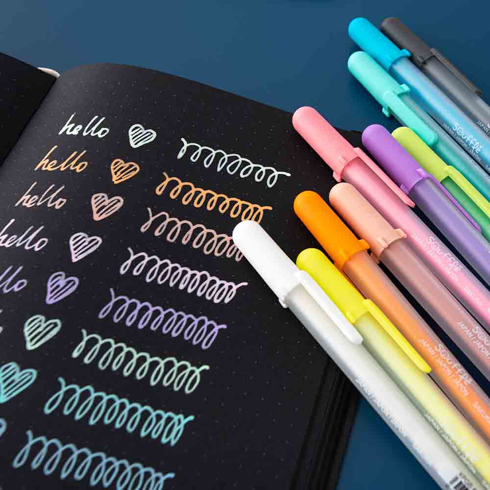 Close up of open Tsuki Black Paper Limited Edition Hardcover Bullet Journal with rainbow Gelly Roll Pens on dark blue background
