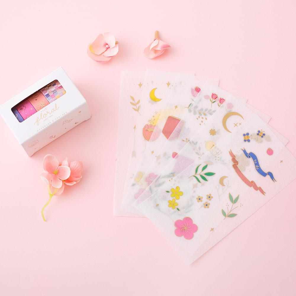 Tsuki Floral collection washi tapes in boxed packaging and 6 sticker sheet laid out on flower ornament and pink background