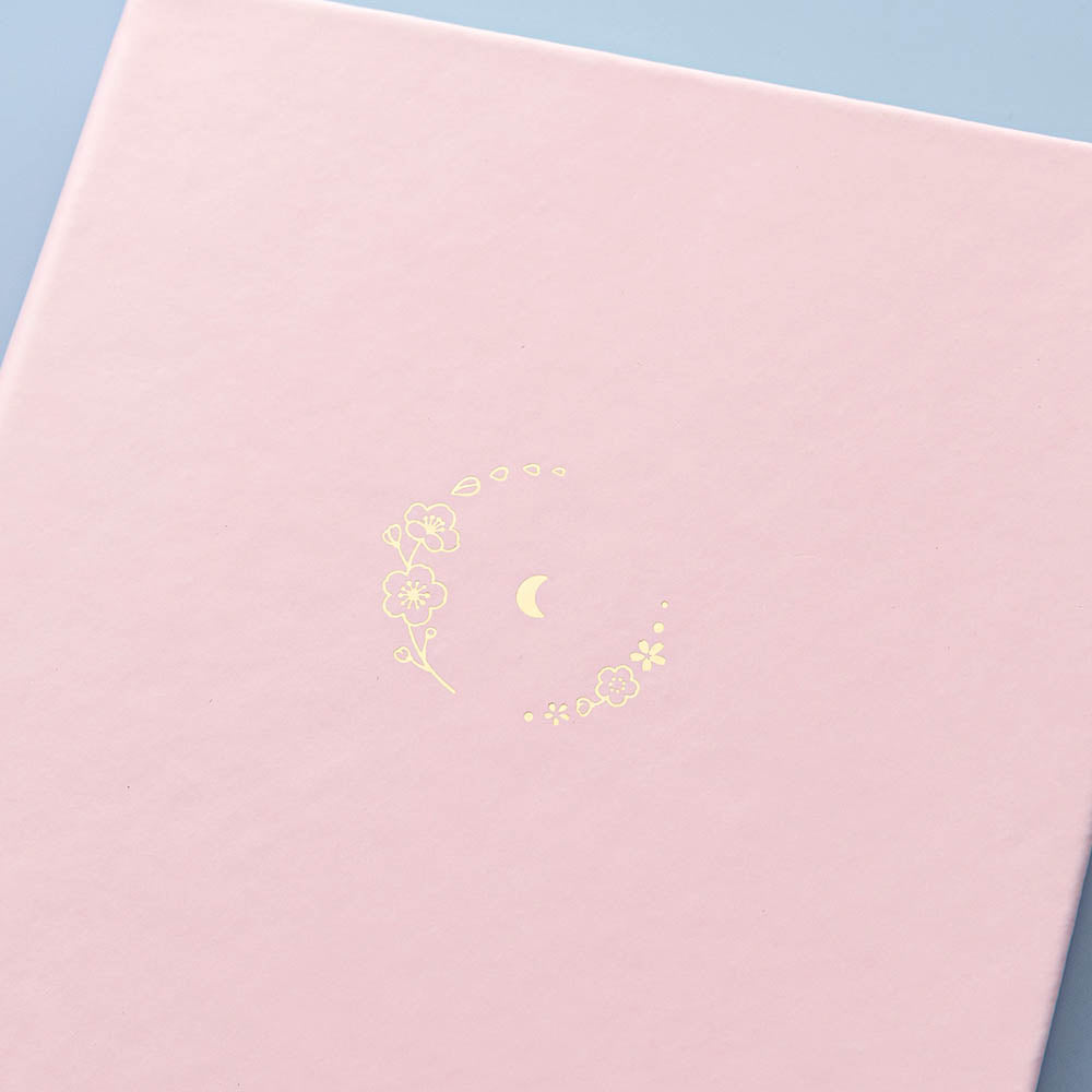 Close up of front cover of Tsuki ‘Lunar Blossom’ Limited Edition Bullet Journal on light blue background