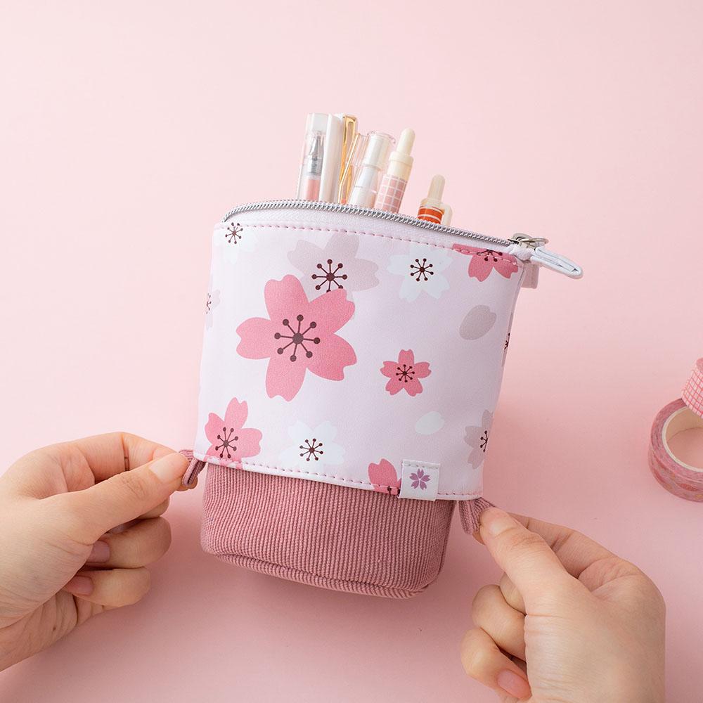 Tsuki 'Sakura Edition' Pop-Up Pencil Case in blush pink with pens inside held in hands over light pink background