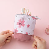 Tsuki 'Sakura Edition' Pop-Up Pencil Case in blush pink with pens inside held in hands over light pink background