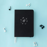 Tsuki Lunar Notes bullet journal with music notes flat lay image on blue background