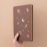 Tsuki ‘Maple Dreams’ Kraft Paper Ringbound Bullet Journal held in hand at spine angle in beige background