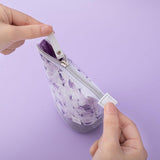 Close up of zip of Tsuki Endless Summer Pop-Up Pencil case in Lilac Bloom held in hands on lilac background