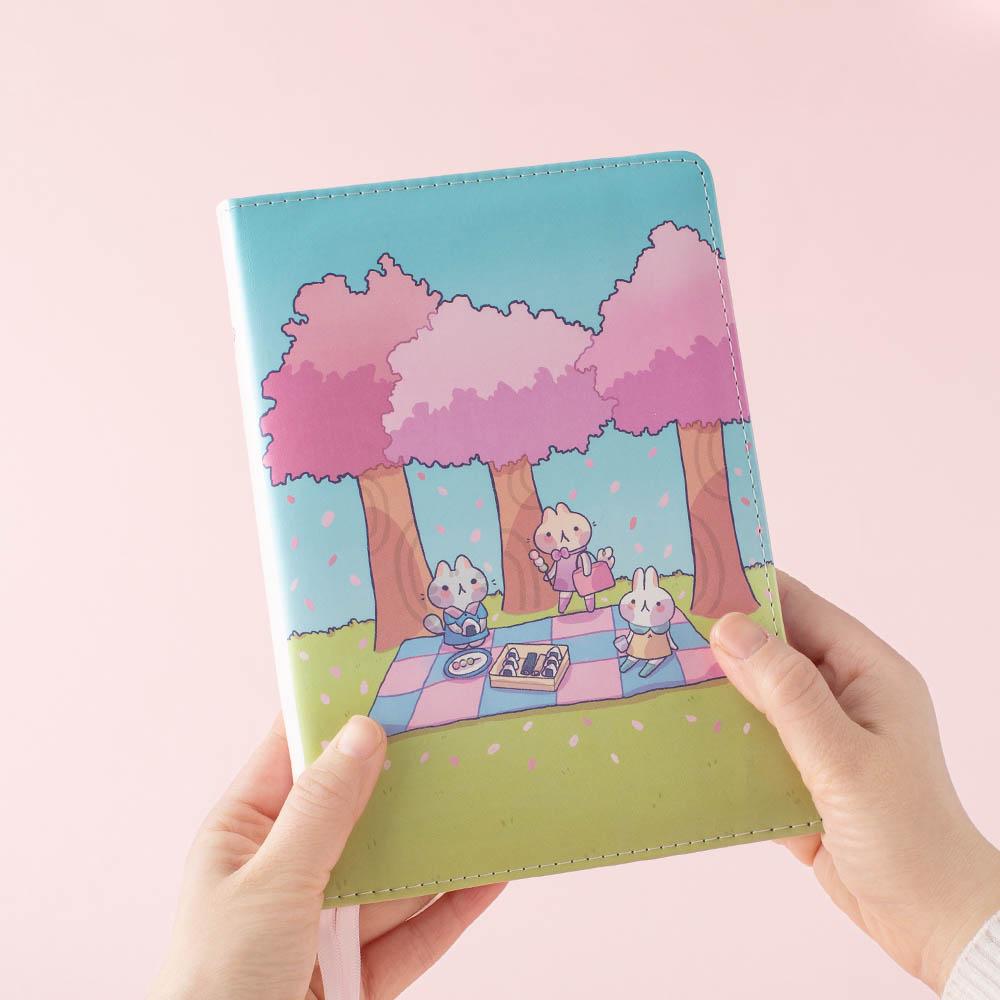 hand holding spring edition bullet journal in pink background
