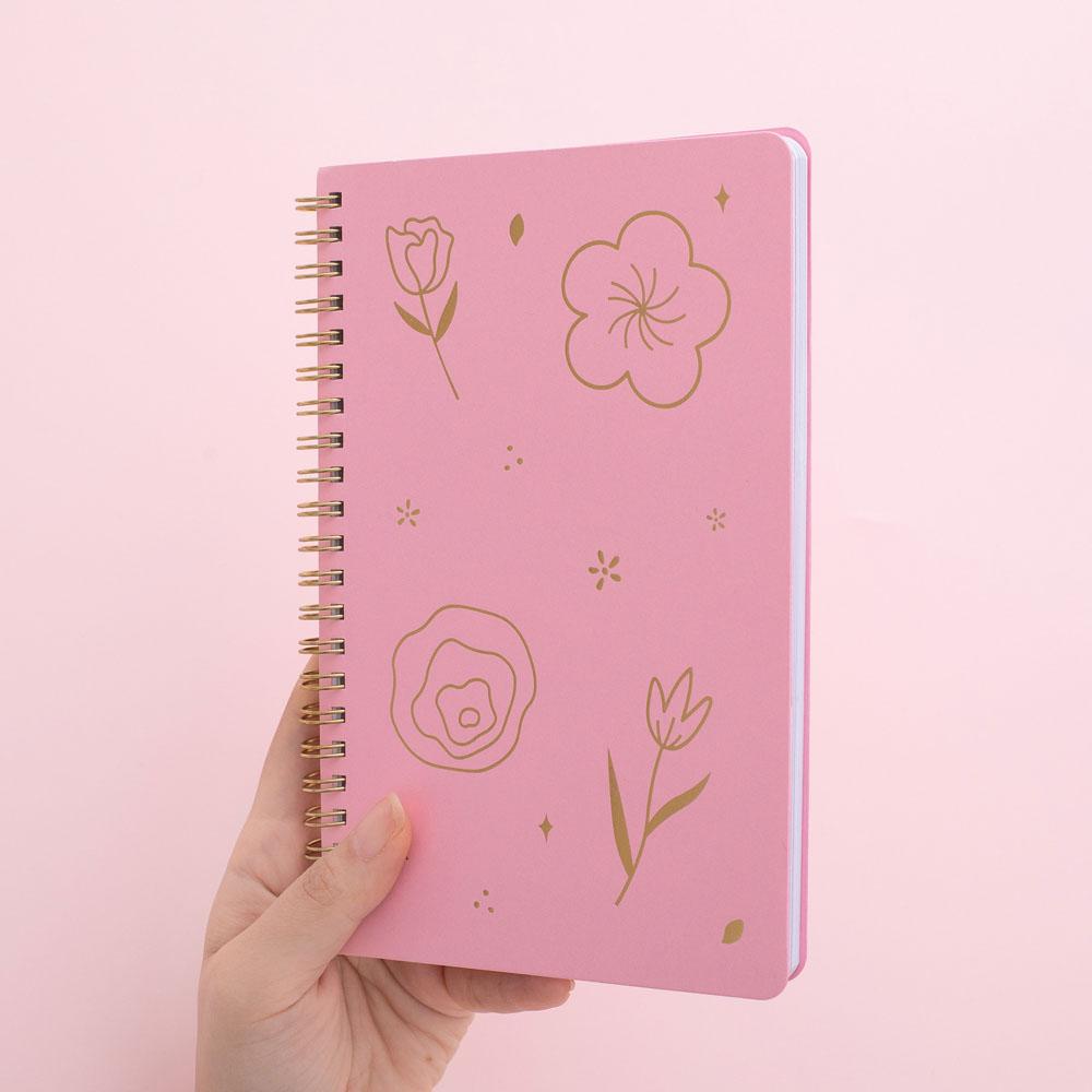 Tsuki sakura pink floral ringbound notebook held in hand at angle in pink background