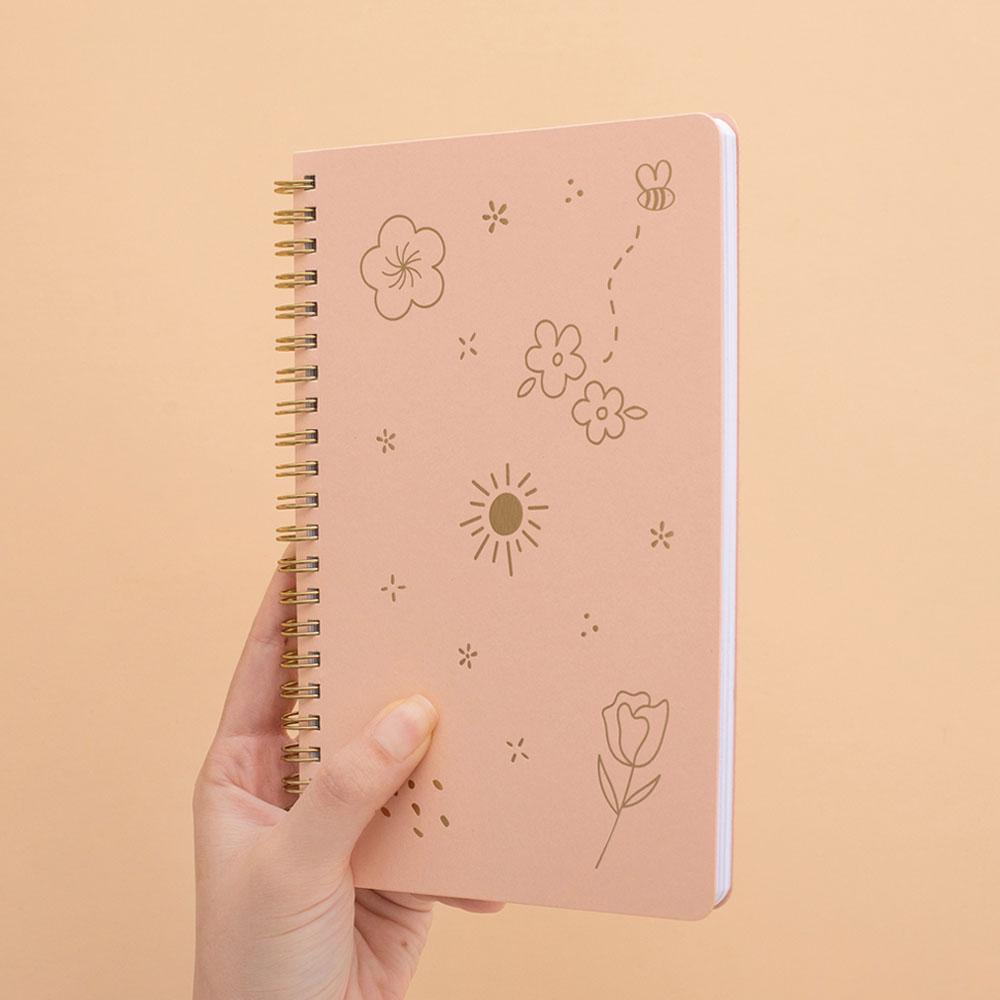 Tsuki honey peach floral ringbound notebook held in hand at angle in peach background