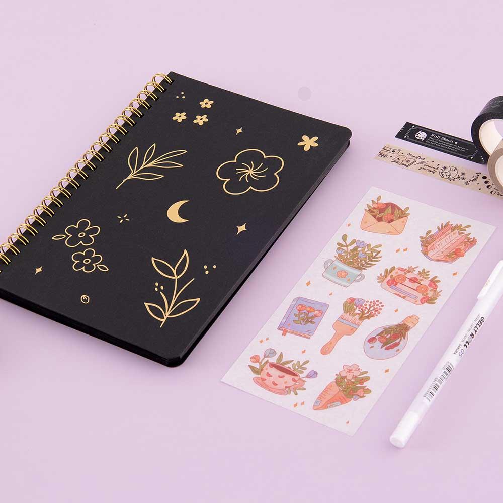 Tsuki Black Paper Ringbound Bullet Journal with free stickers sheet and white Gelly Roll Pen and Tsuki Moonlit Spells Washi Tape on lilac background
