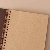 Close up of open front page of Tsuki ‘Maple Dreams’ Kraft Paper Ringbound Bullet Journal on beige background
