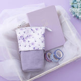 Tsuki Endless Summer Pop-Up Pencil case in Lilac Bloom with Tsuki Endless Summer Washi Tape rolls and Tsuki Endless Summer Limited Edition Bullet Journal in Lilac Bloom in basket with netting with light blue hydrangea flowers on lilac background