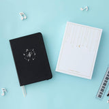 Tsuki Lunar Notes bullet journal with box packaging flat lay image on blue background
