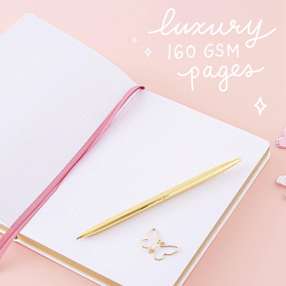 Open page spread of Tsuki Cloud White ‘Flutter + Dream’ Limited Edition Bullet Journal by Notebook Therapy x Pelinkan with luxury 160GSM pages and free butterfly bookmark gift with gold pen and butterflies on pastel pink background