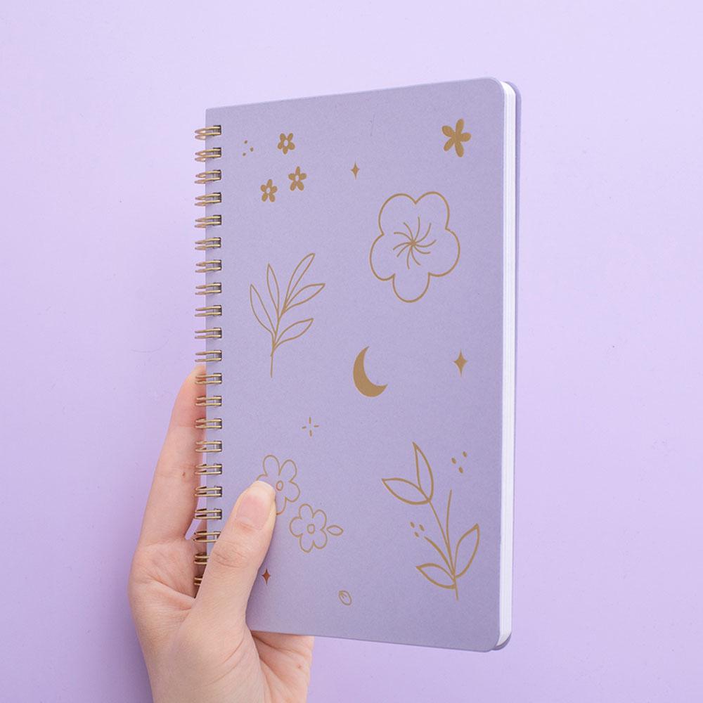 Tsuki lilac taro floral ringbound notebook held in hand at angle in lilac background