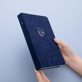 Tsuki deep blue textured vegan leather Gentle Giant luxury edition notebook held in hands at an angle in blue background