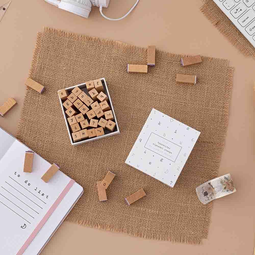 Tsuki Bullet Journal Typewriter Style Alphabet Stamps with eco-friendly gift box packaging and open bullet journal on hessian mat on beige background