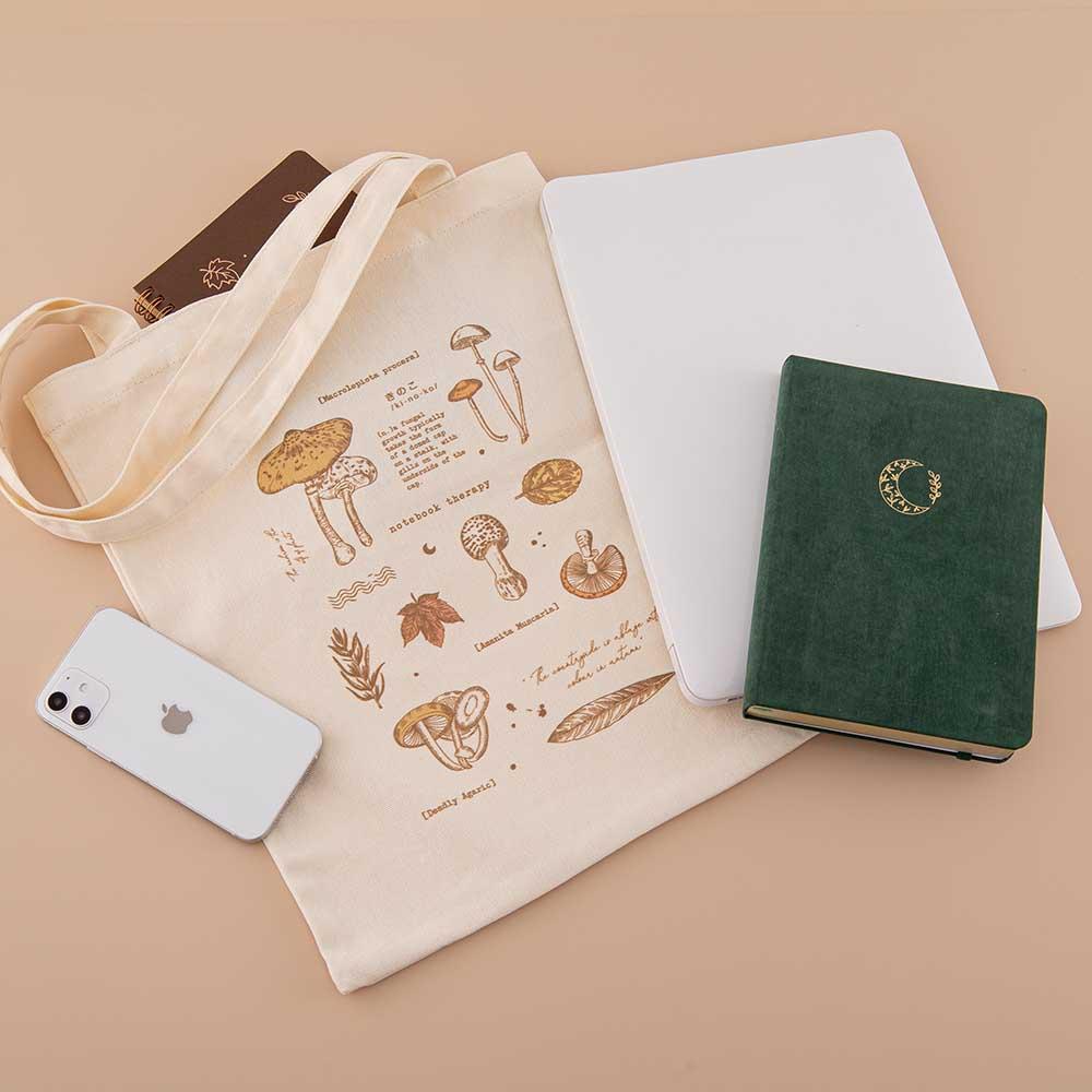 Tsuki ‘Vintage Kinoko’ Tote Bag with Tsuki ‘Maple Dreams’ Kraft Paper Ringbound Bullet Journal and Tsuki ‘Midnight Garden’ Limited Edition notebook with mobile phone and laptop on beige background