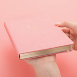 Tsuki ‘Suzume’ Limited Edition Bullet Journal held in hands at an angle in coral pink background