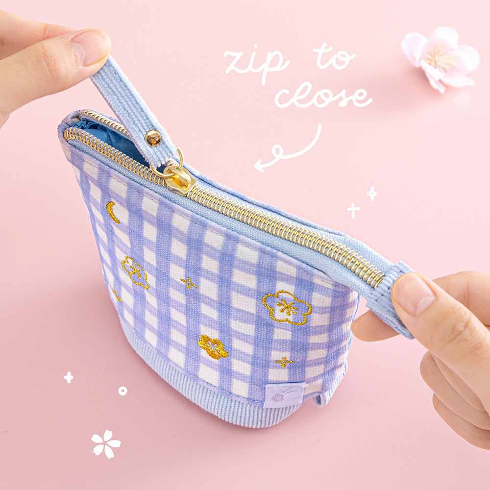 Close up of Tsuki ‘Sakura Journey’ Pop-Up Pencil Case with zip to close held in hands with cherry blossoms on light pink background