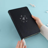 Tsuki Lunar Notes bullet journal in hands image in blue background