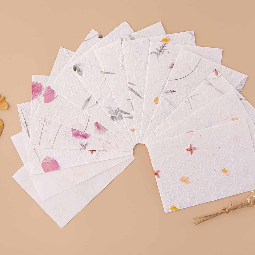 Tsuki Handmade Petal Paper Pack fanned out with dried flowers and autumn leaves on beige background