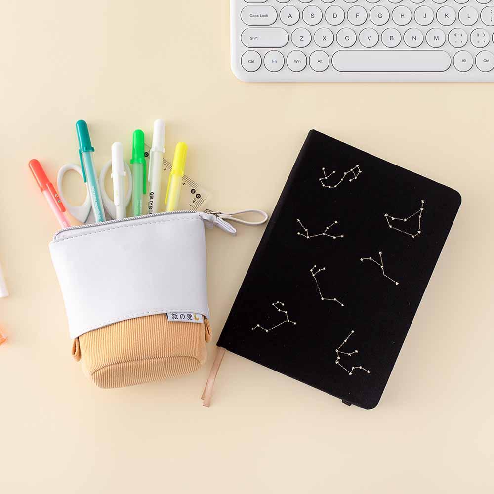 Gelly Roll Pens in Tsuki Pop Up Pencil Case in Honey Butter with Tsuki Black Paper Limited Edition Hardcover Bullet Journal in Constellations with keyboard on buttermilk background