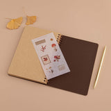 Open Tsuki ‘Maple Dreams’ Kraft Paper Ringbound Bullet Journal with free autumn sticker sheet with autumn leaves and gold pen on beige background