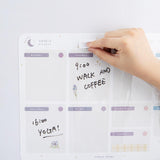 Close up of Tsuki Reusable Weekly Planner with dry erase marker self-adhesive pen holder held in hand on light grey surface