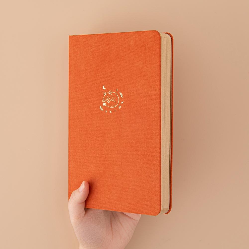Tsuki Kraft Paper Limited Edition Bullet Journal in Kitsune held in hand at spine angle in beige background