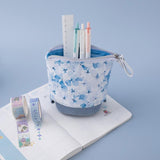Tsuki Endless Summer Pop-Up Pencil case in Petal Blue with pens and ruler with Tsuki Endless Summer Washi Tape Rolls and open bullet journal on light blue background