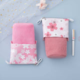 Tsuki 'Sakura Edition' Pop-Up Pencil Case in blush pink and petal pink with white pen and sakura blooms on sparkly netting on light blue background