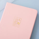 Tsuki 'Sakura' Limited Edition Bullet Journal in petal pink on light blue background
