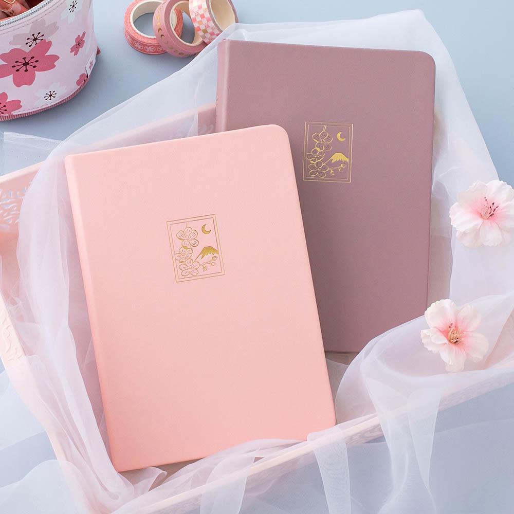 Tsuki 'Sakura' Limited Edition Bullet Journal in blush pink and petal pink with sakura blooms in netted basket on light blue background