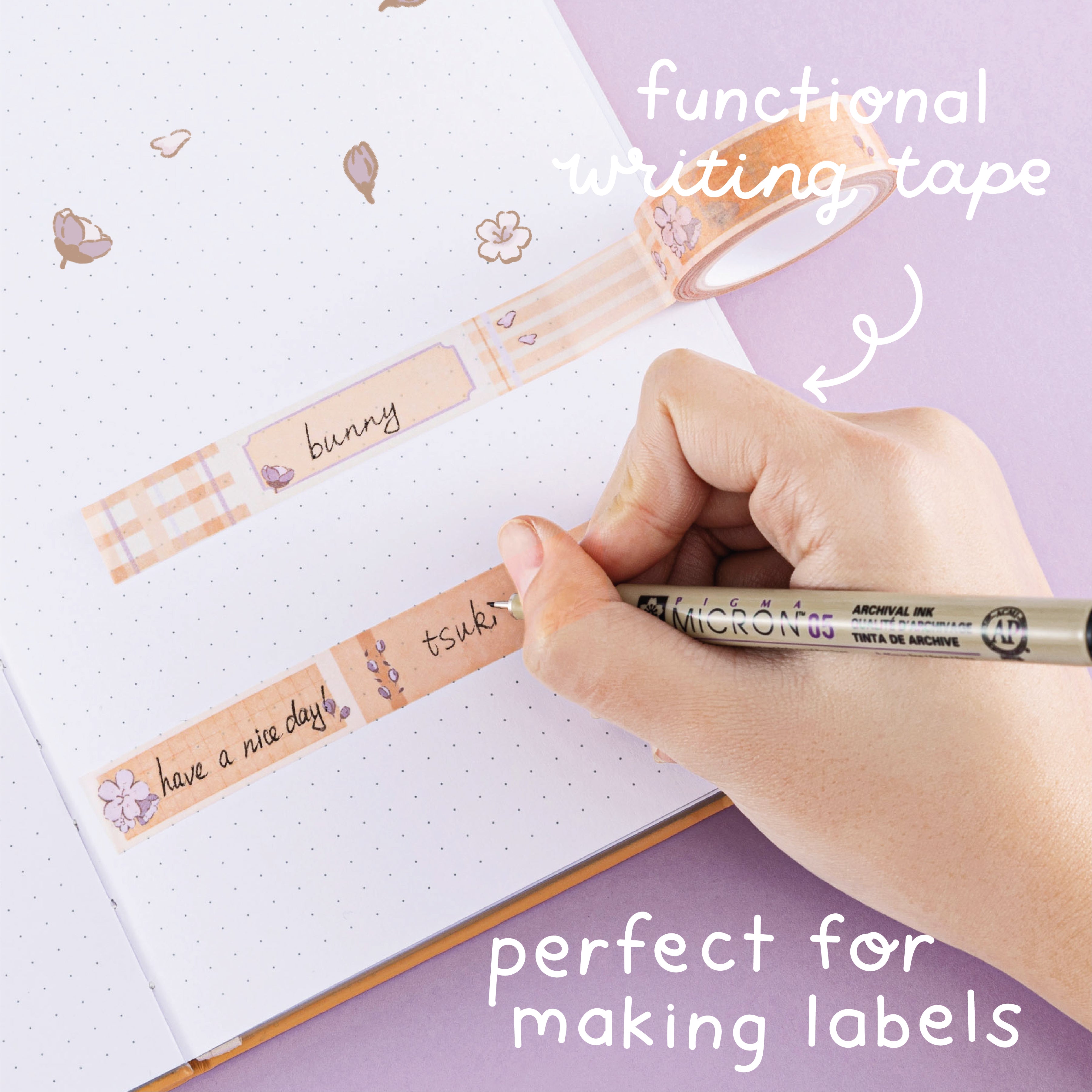 Functional writing tape from Tsuki Bunny Blush Washi Tape Set designed with Blossom Bujo rolled out on open bullet journal with pen held in hand on lilac background