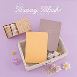Tsuki Honey Butter ‘Bunny Blush’ Limited Edition Bullet Journal with Tsuki Blush Pink ‘Bunny Blush’ Limited Edition Bullet Journal in basket and Tsuki ‘Bunny Blush’ Washi Tape Set designed with Blossom Bujo with felt flowers on lilac background