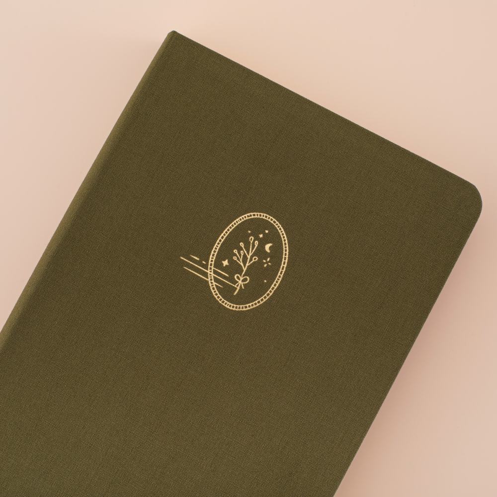 Close up of tsuki mori green linen bullet journal with a plant design in gold foil