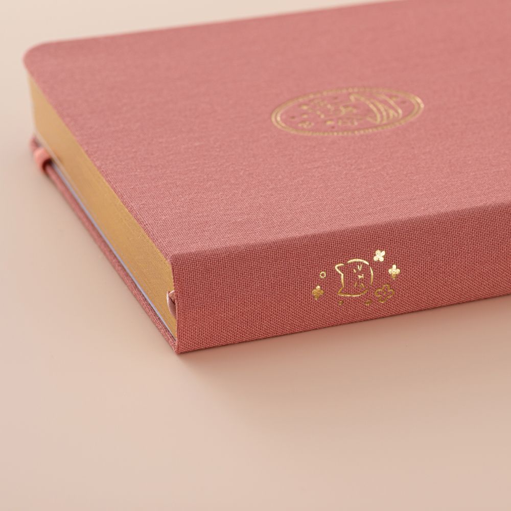 Close up of the gold details on the spine of a pink linen bullet journal
