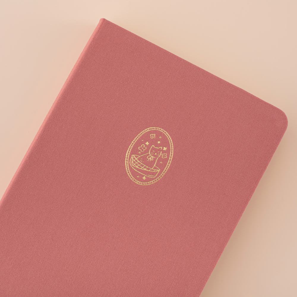 Close up of tsuki cat pink linen bullet journal with a cat design in gold foil