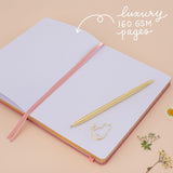 Notebook laid flat on beige background with the words ‘luxury 160gsm pages’ in white lettering