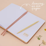 Notebook laid flat on beige background with the words ‘luxury 160gsm pages’ in white lettering