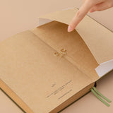 Kraft paper notebook and a hand opening the expandable back pocket