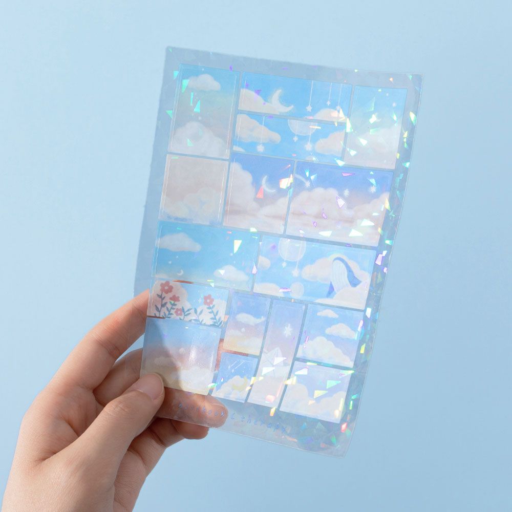 Hand holding shiny glitter sticker sheet with cloud designs