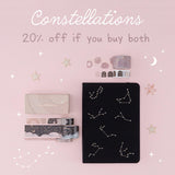 Constellations collection flatlay with black bullet journal on pink background - 20% off if you buy both